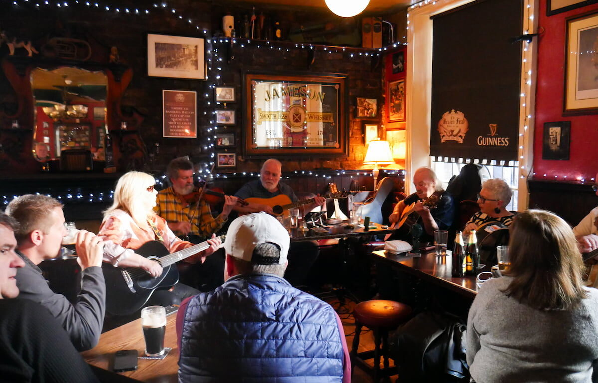 Guests enjoy live folk music session in cosy pub with warm lighting and friendly atmosphere at hotel.