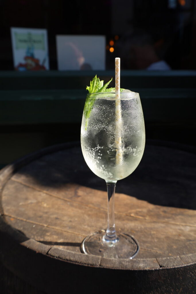 Refreshing cocktail with mint garnish on rustic barrel, perfect for sunny hotel patio relaxation.
