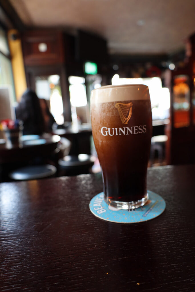 Cosy pub with a pint of Guinness on a wooden table, offering a warm ambiance for hotel guests seeking relaxation.