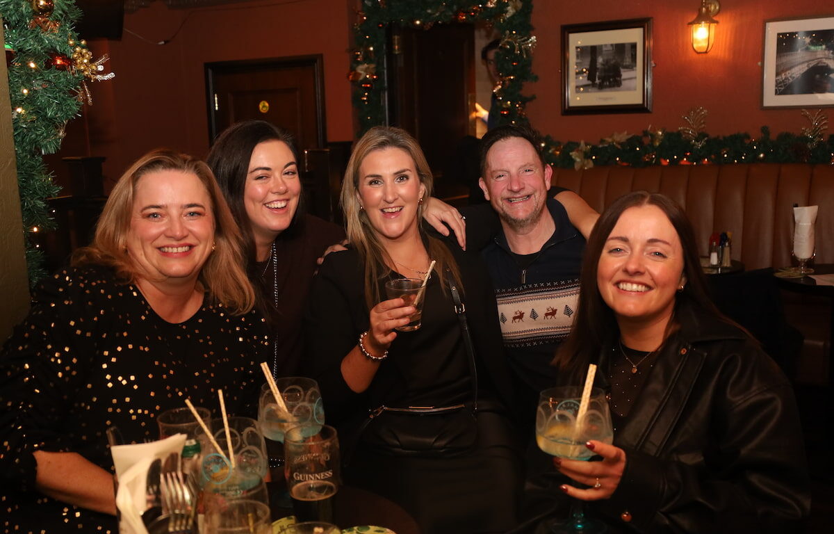 Guests enjoy festive drinks and warm ambience in hotel lounge, adorned with holiday decor and cosy lighting.
